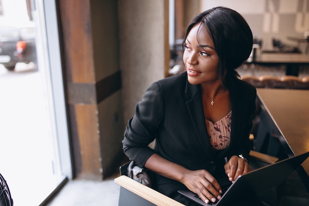 Mujer de negocios afroamericana trabajando en una computadora en un bar