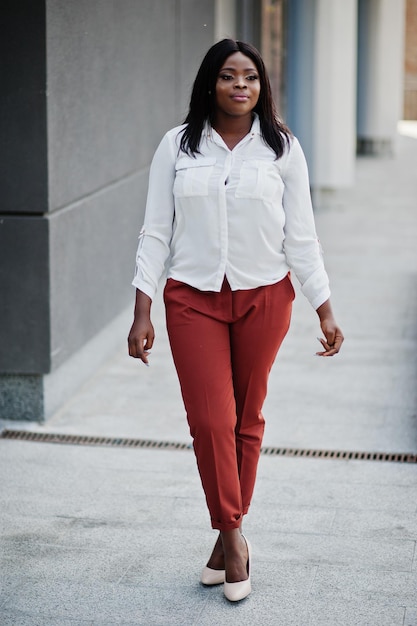 Mujer de negocios afroamericana vestida formalmente con blusa blanca y pantalones rojos Exitosa mujer de negocios de piel oscura