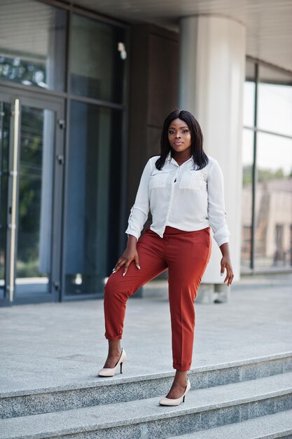 Mujer de negocios afroamericana vestida formalmente con blusa blanca y pantalones rojos Exitosa mujer de negocios de piel oscura