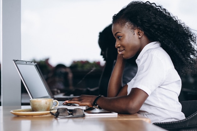 Mujer de negocios afroamericano con computadora y teléfono en un café