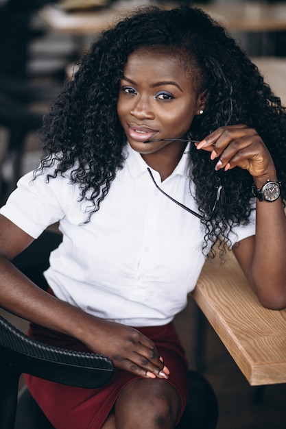 Mujer de negocios afroamericano sentado en un bar con computadora