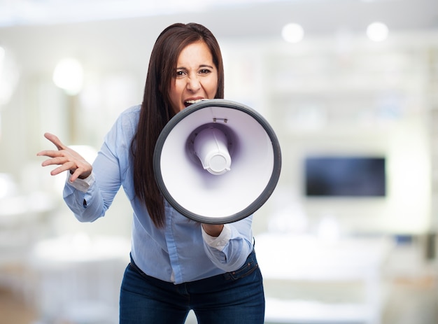 Mujer de negocios agobiada utilizando un altavoz con el fondo borroso