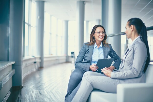 Mujer de negocios alegre hablando con su compañera