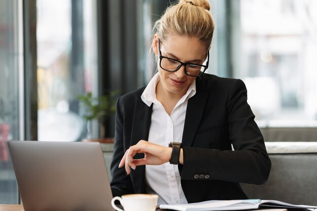 Mujer de negocios alegre mirando el reloj.