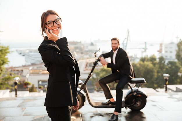 Mujer de negocios alegre posando al aire libre y hablando por teléfono