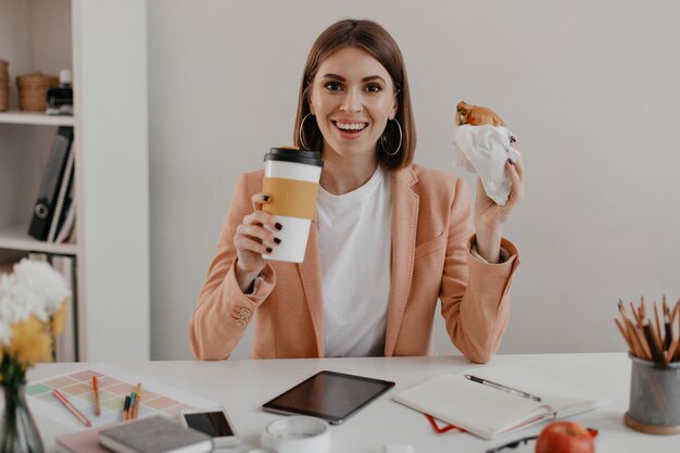 Mujer de negocios alegre con una sonrisa mientras almuerza en la oficina brillante.