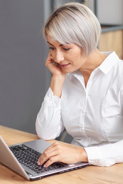 Mujer de negocios de alto ángulo que trabaja en la computadora portátil