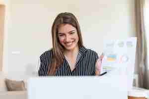 Foto gratuita mujer de negocios analizando datos usando la computadora mientras pasa tiempo en la oficina hermosa joven mujer profesional sonriente en la oficina gráficos y tablas