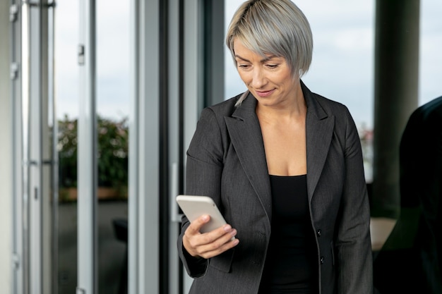 Mujer de negocios de ángulo bajo mirando el teléfono