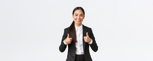 Una mujer de negocios asiática sonriente y segura de sí misma asegura que todo va bien mostrando el pulgar hacia arriba recomendar agencia o producto como y aprobar decir bien hecho buen trabajo o buen trabajo