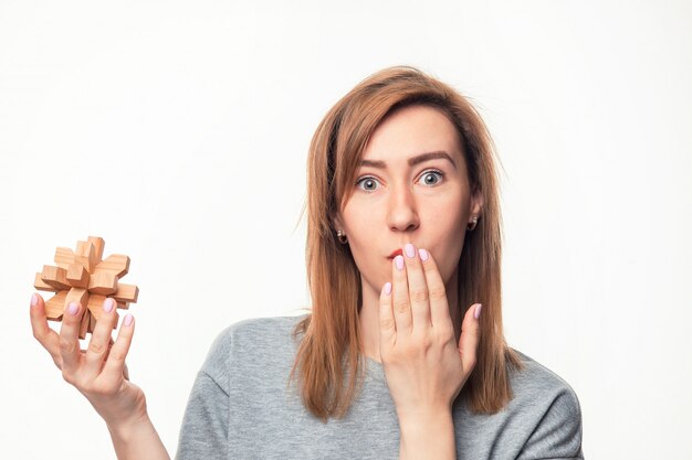 Mujer de negocios atractiva de 24 años que parece confundida con rompecabezas de madera.