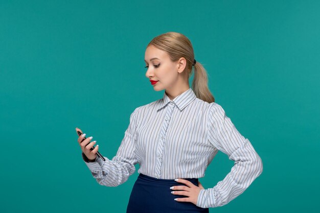 Mujer de negocios bastante rubia en traje de oficina mirando el teléfono