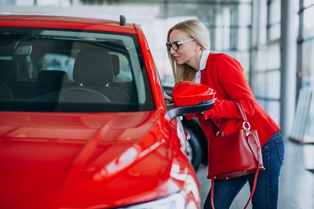 Mujer de negocios buscando un auto móvil en una sala de exposición de automóviles