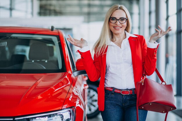 Mujer de negocios buscando un auto móvil en una sala de exposición de automóviles