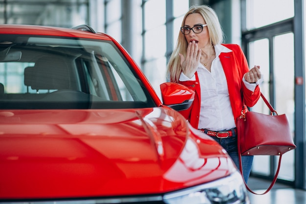 Mujer de negocios buscando un auto móvil en una sala de exposición de automóviles