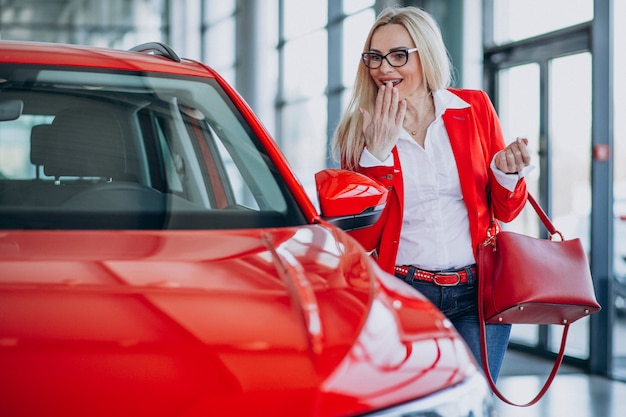 Mujer de negocios buscando un auto móvil en una sala de exposición de automóviles