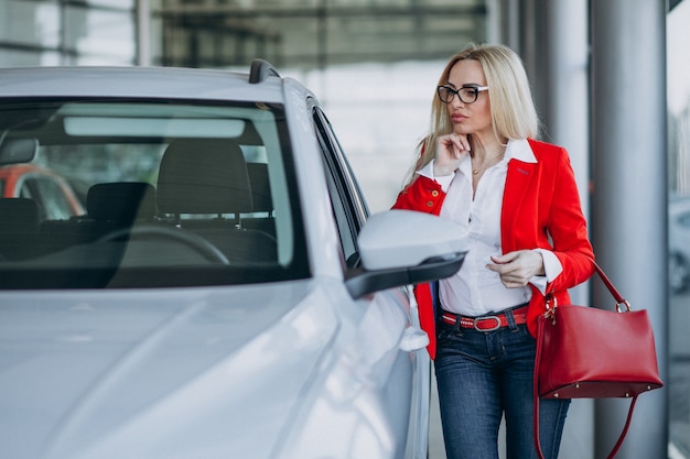 Mujer de negocios buscando un auto móvil en una sala de exposición de automóviles