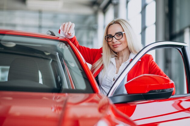 Mujer de negocios buscando un auto móvil en una sala de exposición de automóviles