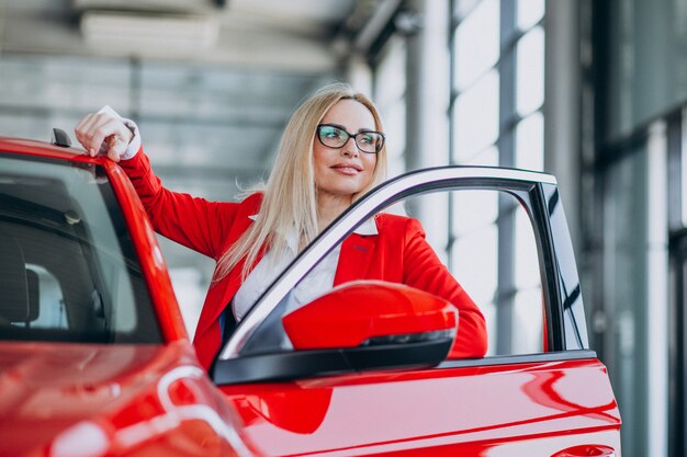 Mujer de negocios buscando un auto móvil en una sala de exposición de automóviles