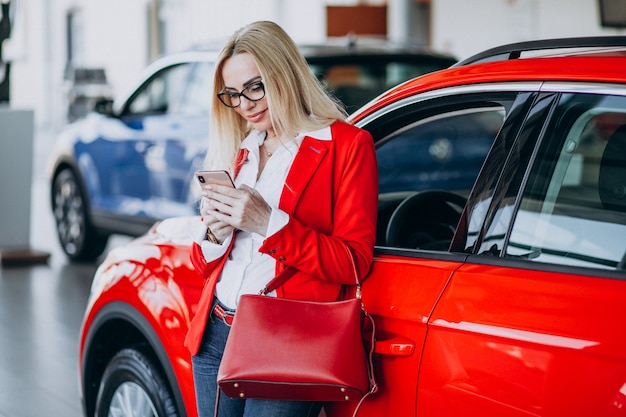 Mujer de negocios buscando un auto móvil en una sala de exposición de automóviles