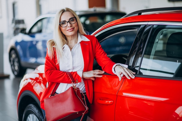 Mujer de negocios buscando un auto móvil en una sala de exposición de automóviles