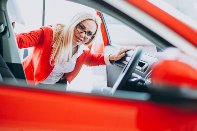 Mujer de negocios buscando un auto móvil en una sala de exposición de automóviles