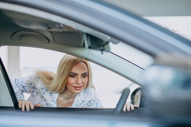 Mujer de negocios buscando un auto móvil en una sala de exposición de automóviles