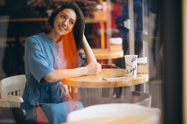 Mujer de negocios con café y teléfono en una cafetería