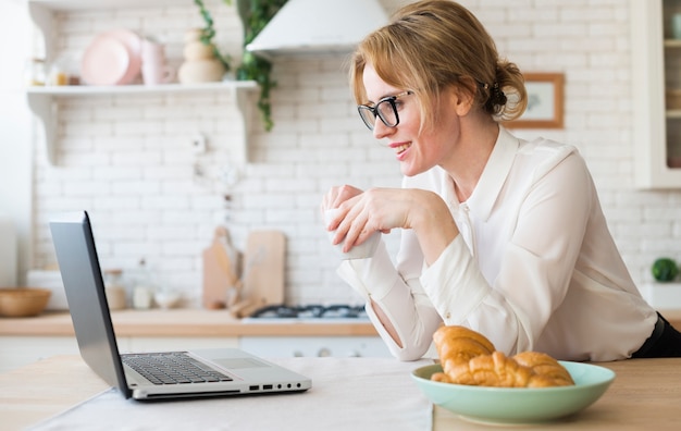 Mujer de negocios con café usando laptop