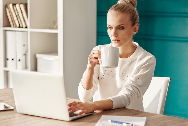 Mujer de negocios, con, café, usar la computadora portátil