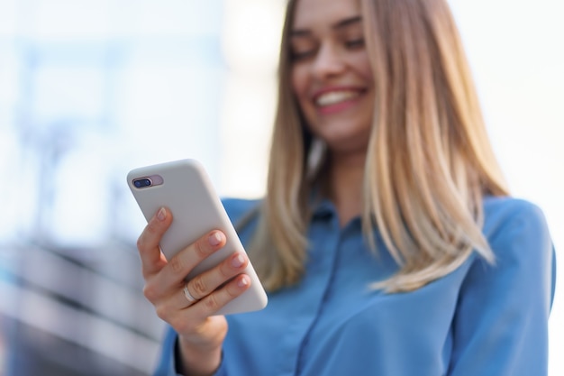 Foto gratuita mujer de negocios caucásica hablando por teléfono con café para llevar. una mujer europea exitosa, hablando por teléfono, de pie en el edificio de oficinas moderno