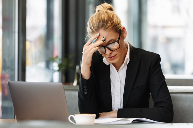 Mujer de negocios concentrada escribiendo notas en el cuaderno.