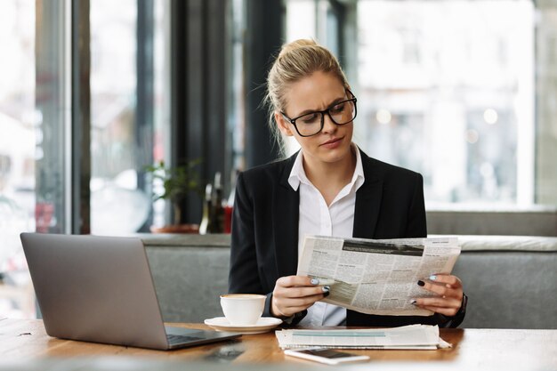 Mujer de negocios concentrada leyendo el periódico.