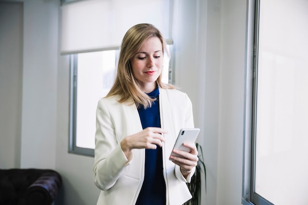 Mujer de negocios contenta mirando a smartphone