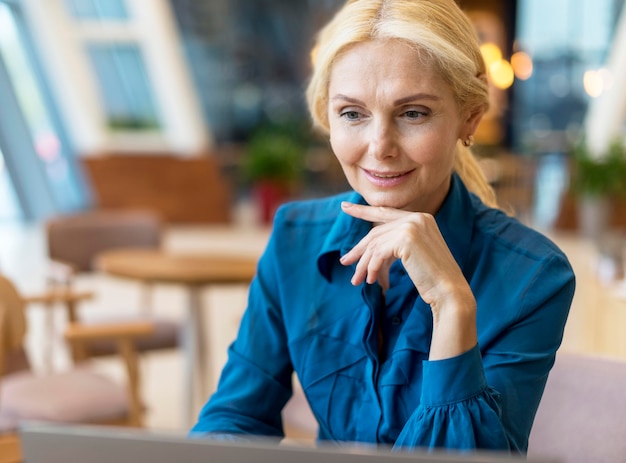 Mujer de negocios de edad trabajando en el portátil en un comedor