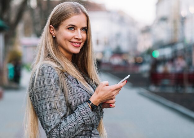 Mujer de negocios elegante usando smartphone en ciudad