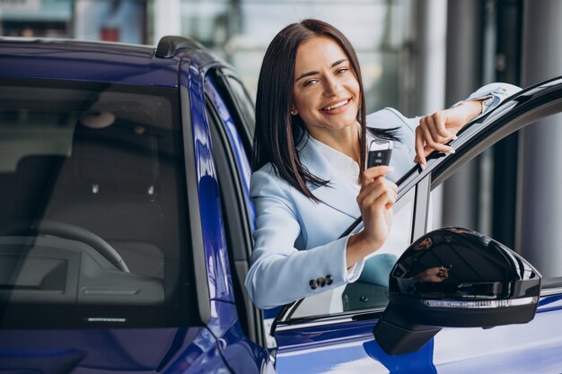 Mujer de negocios eligiendo un coche en una sala de exposición de coches