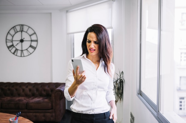 Mujer de negocios enfadada mirando a smartphone