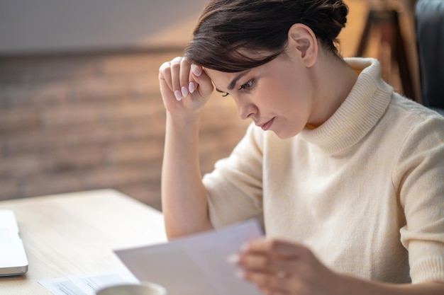 Mujer de negocios enfocada inclinada sobre un contrato