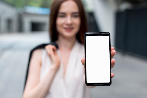 Mujer de negocios enseñando smartphone en la calle