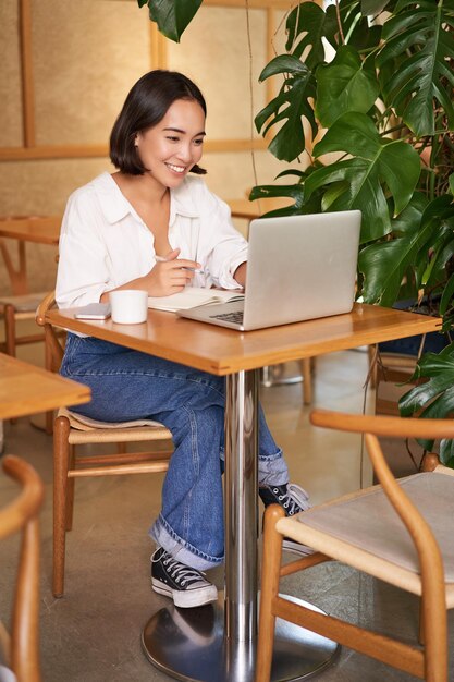 Mujer de negocios con estilo con una computadora portátil sentada en un café y trabajando en negocios de administración de computadoras y bebidas