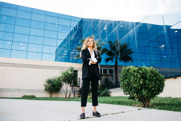 Mujer de negocios con estilo enfrente de edificio de cristal