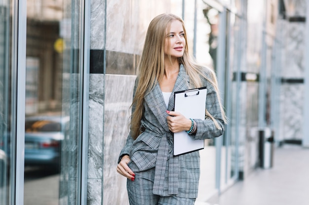 Mujer de negocios de estilo con portapapeles en ciudad