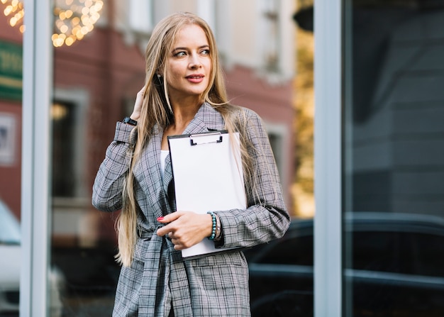 Mujer de negocios de estilo con portapapeles en ciudad