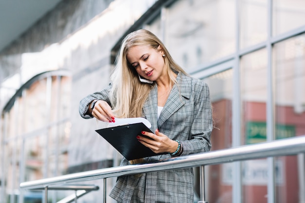 Mujer de negocios de estilo con portapapeles en ciudad