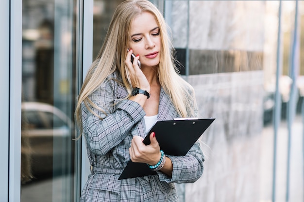 Foto gratuita mujer de negocios de estilo con portapapeles haciendo llamada