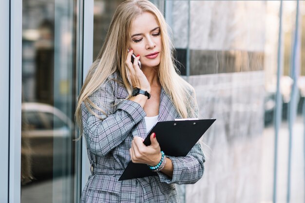 Mujer de negocios de estilo con portapapeles haciendo llamada