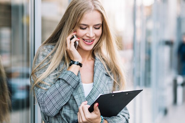 Mujer de negocios de estilo con portapapeles haciendo llamada