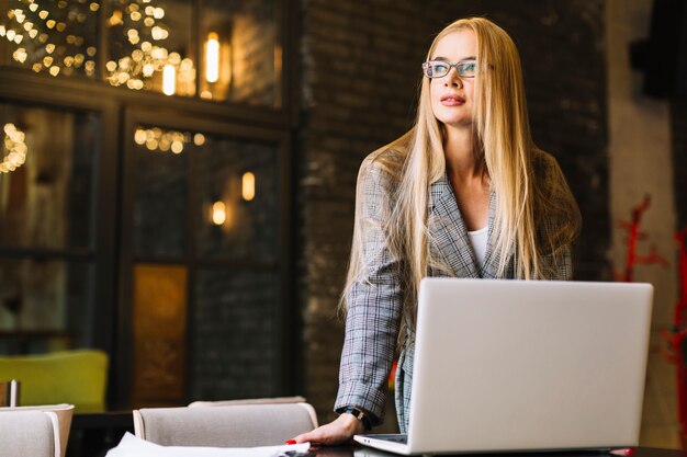 Mujer de negocios de estilo con portátil en cafetería agradable