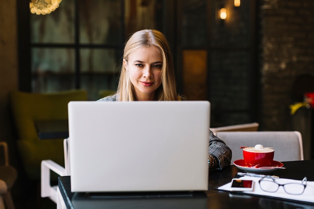 Mujer de negocios de estilo con portátil en cafetería agradable